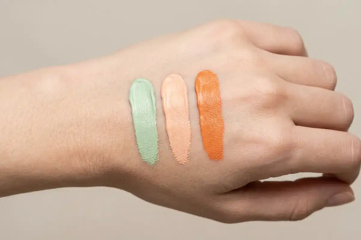 Correcteurs colorés de maquillage Swatches de correcteurs vert, pêche et orange déposés sur le dos d une main