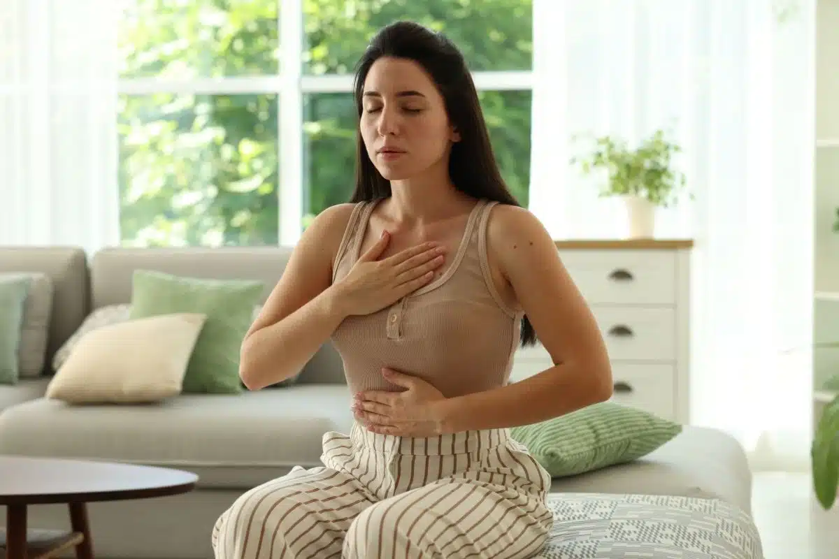 Symptômes physiques d'une crise d'angoisse Femme portant la main à sa poitrine, signe d'oppression thoracique pendant une crise d'angoisse