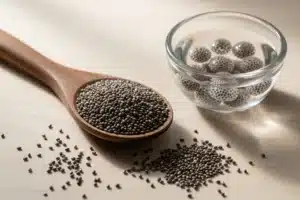 Graines de chia noires dans une cuillère en bois sur fond naturel, illustrant leur utilisation alimentaire quotidienne