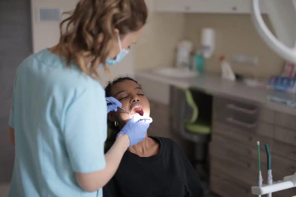 Traitement de racine sur une molaire Dentiste réalisant un soin dentaire dans la bouche d’une patiente au fauteuil
