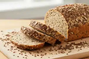 Pain sans gluten aux graines tranché sur une planche en bois, mie dense