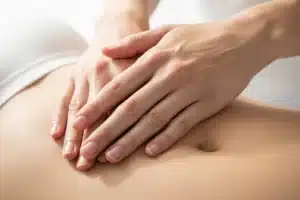 Mains posées doucement sur l'abdomen dans la zone du plexus solaire