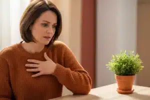 Spasmophilie : femme la main posée sur la poitrine, signe d'oppression thoracique