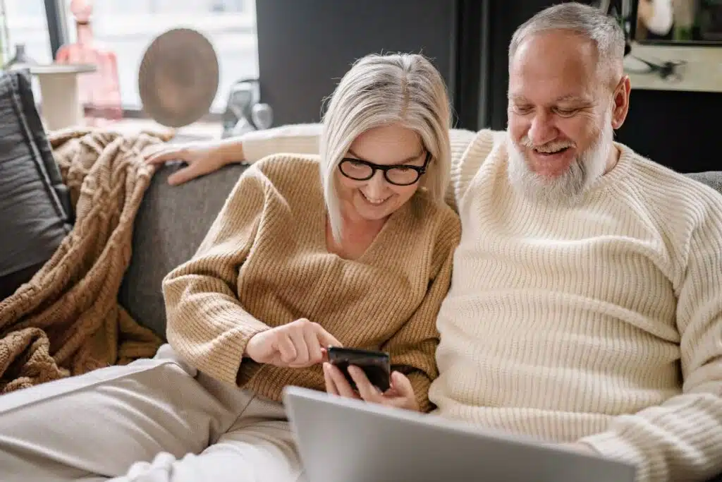 Couple de seniors souriant consultant ensemble un smartphone dans leur salon
