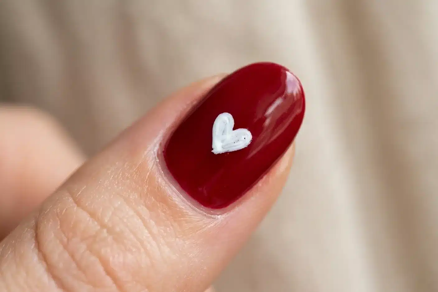 Motif coeur nail art saint-valentin Gros plan ongle rouge avec motif coeur blanc tracé au cure-dent