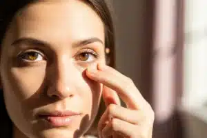 Paupière qui tremble : femme portant un doigt près de sa paupière inférieure
