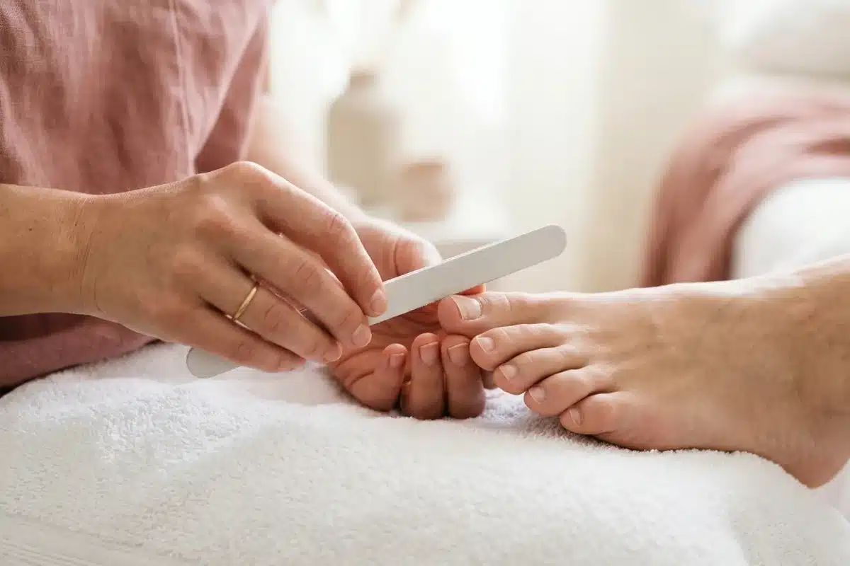 Limage des ongles d'orteils en preparation de la french manucure Mains preparant un ongle d'orteil avec une lime a ongles avant la pose de french manucure