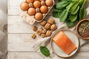 Aliments bons pour les cheveux sur une table en bois : oeufs, épinards, noix, saumon et graines