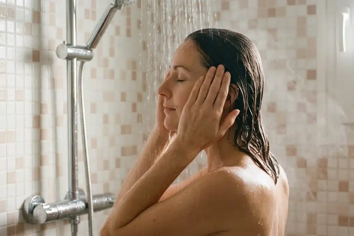 Routine capillaire massage cuir chevelu Femme de profil effectuant un massage du cuir chevelu sous la douche