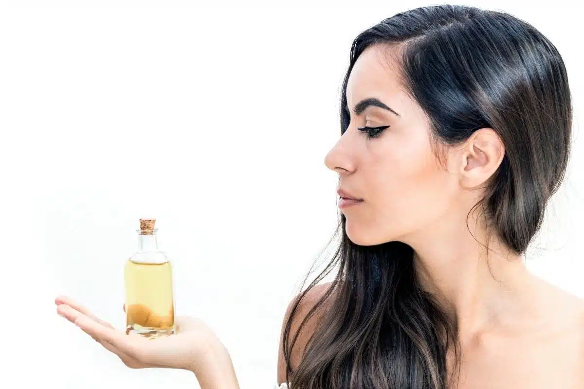 Huile d'avocat cosmétique en flacon de verre Femme tenant un flacon d'huile d'avocat cosmétique dans le creux de sa main
