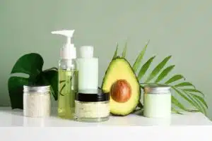 Flacon d'huile d'avocat et soins cosmétiques avec un demi-avocat et du feuillage vert