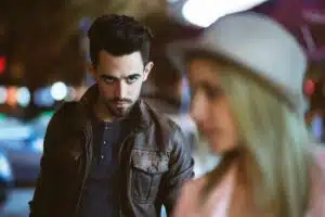 Homme en veste de cuir fixant intensément une femme dans une rue le soir, illustrant les signes du désir masculin