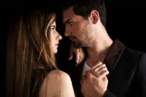Un homme et une femme face à face dans une lumière tamisée, regards intenses évoquant l'attirance physique sans sentiment amoureux