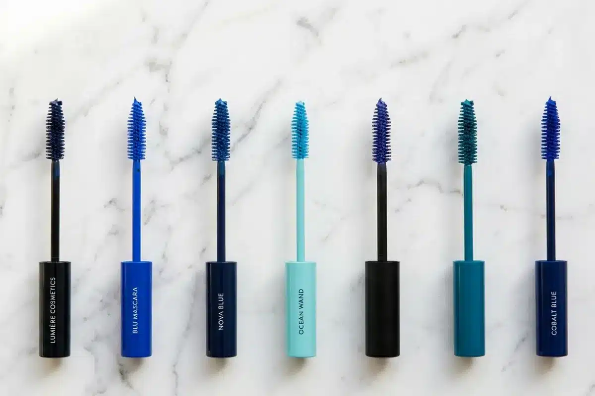 Tubes de mascaras bleus en différentes nuances Collection de mascaras bleus en nuances variées, du marine au turquoise, en flat lay sur marbre blanc