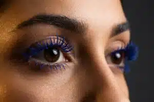 Gros plan de cils ornés de mascara bleu cobalt intense, regard féminin sublimé